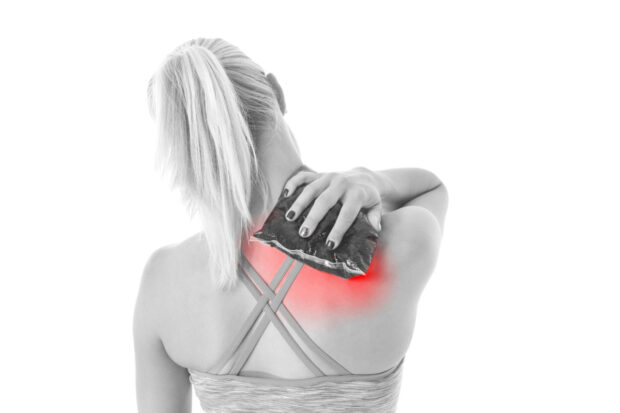 Acute pain in a woman shoulder. Female holding hand to spot of shoulder-aches.